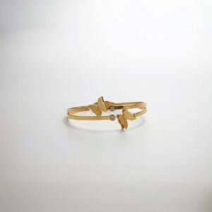 A close-up of an elegant gold-plated cuff bracelet featuring two frosted butterfly designs and two small, sparkling diamond-like accents, presented on a clean white background.