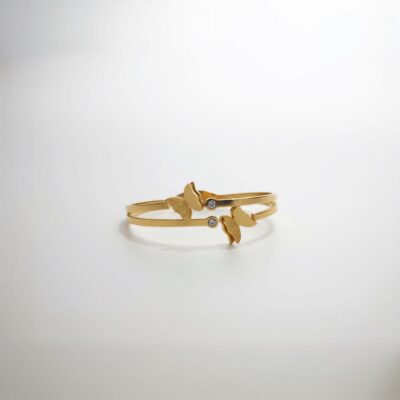 A close-up of an elegant gold-plated cuff bracelet featuring two frosted butterfly designs and two small, sparkling diamond-like accents, presented on a clean white background.